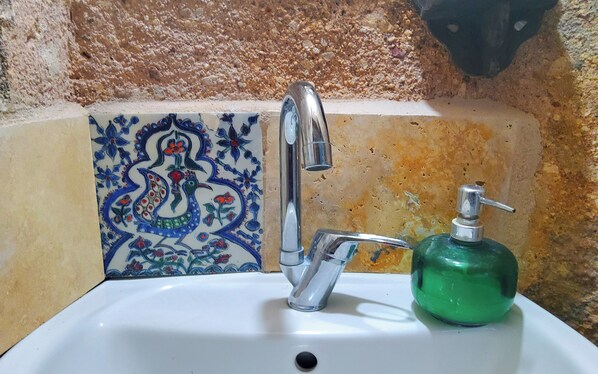 A bathroom sink with a modern faucet and a green soap dispenser.