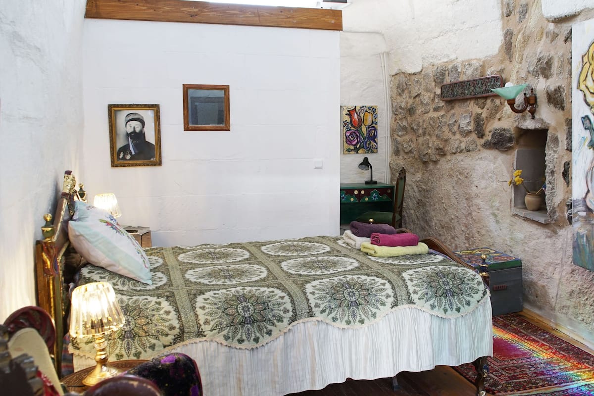 Une chambre à coucher avec un lit, une table de chevet, une lampe, une commode et un tableau au mur.