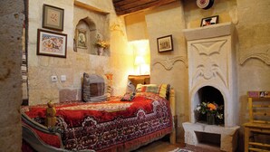 A traditional room with a bed, a fireplace, and wall-mounted pictures. - Dancing Cloud Art Pansion (Nevsehir)