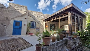 A traditional stone building with a blue door, wooden beams, and potted plants. - Dancing Cloud Art Pansion (Nevsehir)
