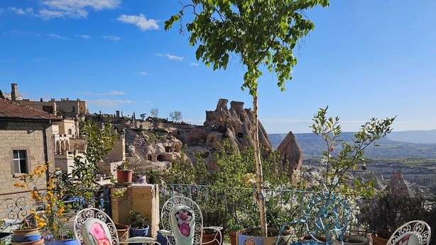 A patio with stone flooring and metal chairs, overlooking a mountainous landscape with traditional buildings. - Dancing Cloud Art Pansion (Nevsehir)