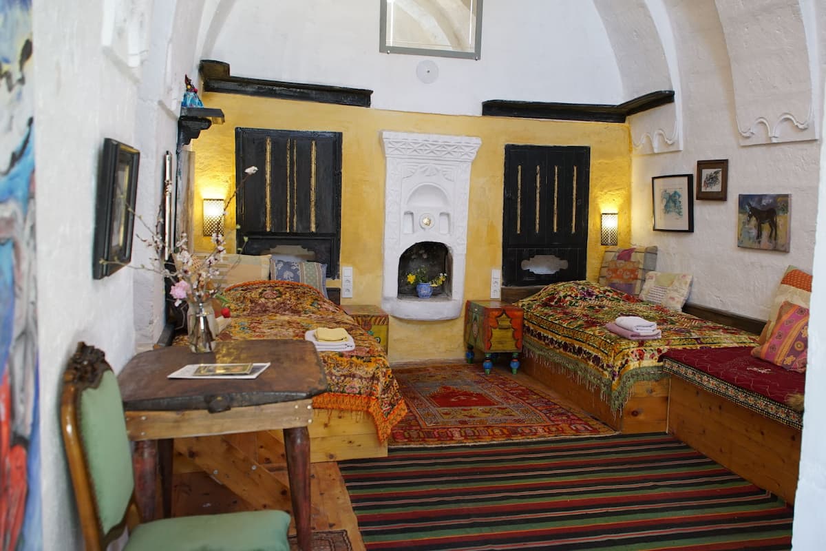 Une chambre de style traditionnel, dotée de deux lits, d’une cheminée et d’une petite table.