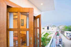 Une porte en bois avec des panneaux de verre, une chaise et une plante en pot, visibles à travers la porte.