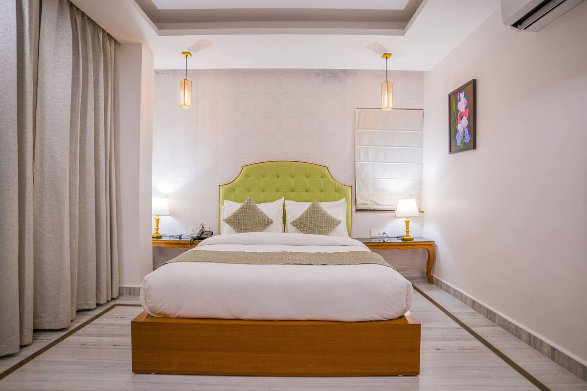 Una habitación de hotel con una cama grande, dos mesitas de noche y un cabecero.