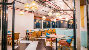 Un restaurant amb cadires de vimbles, taules i llums penjants.