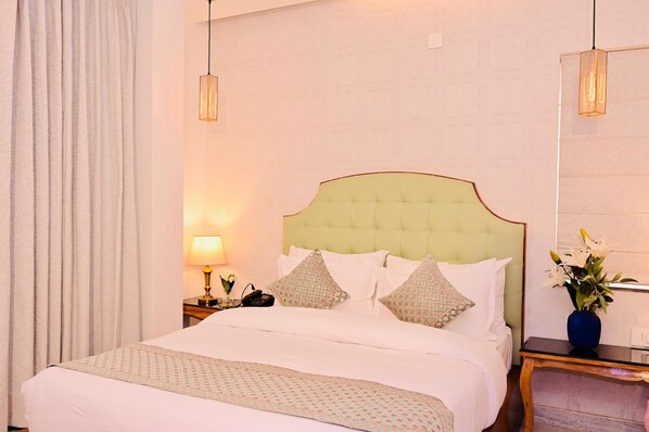 A hotel room with a large bed, a nightstand with a lamp, and a vase with flowers.