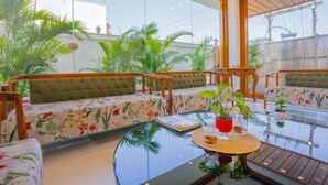 Zona d'estar moderna amb dos sofàs amb coixins verds, una taula de centre de vidre i plantes en testos.