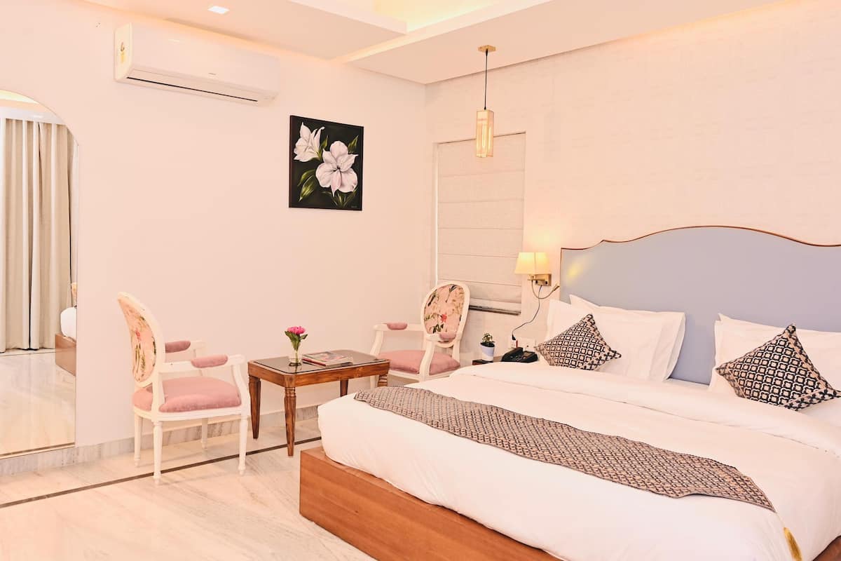 Una habitación de hotel con cama, mesita de noche, silla y un espejo grande.