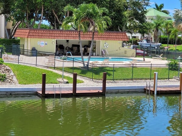 A pool area with a covered seating area, a lifeguard stand, and a small building with a red roof. - 2BR waterfront Marco Island condo with pool, WiFi, and heated pool. (Marco Island)