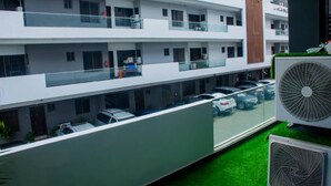 A multi-story residential building with balconies, a parking area, and outdoor air conditioning units. - Lawview Residential Services Apartment (Lekki)