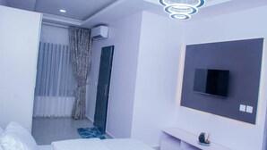 A modern bedroom with a bed, a TV mounted on the wall, and a ceiling light fixture. - Lawview Residential Services Apartment (Lekki)