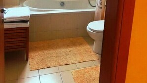 A small bathroom with a bathtub, toilet, and a window. - 2 bedroom with private garden, walk to Nissi Beach
 (Ayia Napa)