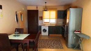A compact living space with a dining area, kitchen, and a small ironing station. - 2 bedroom with private garden, walk to Nissi Beach
 (Ayia Napa)