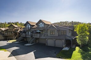 Una casa a più piani con un garage, un portico coperto e una scala che conduce ai piani superiori.