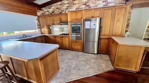 A kitchen with wooden cabinets, a stainless steel refrigerator, and a built-in oven. - Beautiful house, located in a quiet area of town with its own private pool (South West Rocks)