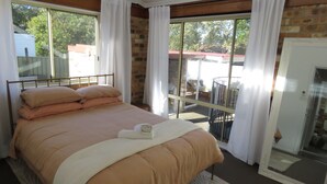 A bedroom with a bed, a window, and a door. - Beautiful house, located in a quiet area of town with its own private pool (South West Rocks)