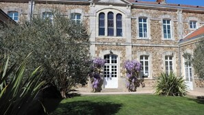 A stone building with a central entrance, large windows, and a bell tower. - La Maison D'olivier Avec Piscine Privatif (Mesnard-la-Barotière)