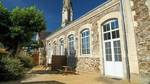 A stone building with a church steeple, arched windows, and a wooden bench. - La Maison D'olivier Avec Piscine Privatif (Mesnard-la-Barotière)