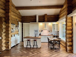 A log cabin-style kitchen with a central island, white cabinetry, and a herringbone wood floor.