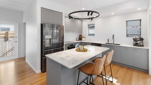 A modern kitchen with a central island, stainless steel appliances, and a pendant light.