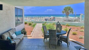Un balcón con vista a la playa, mobiliario exterior y zona de comedor.