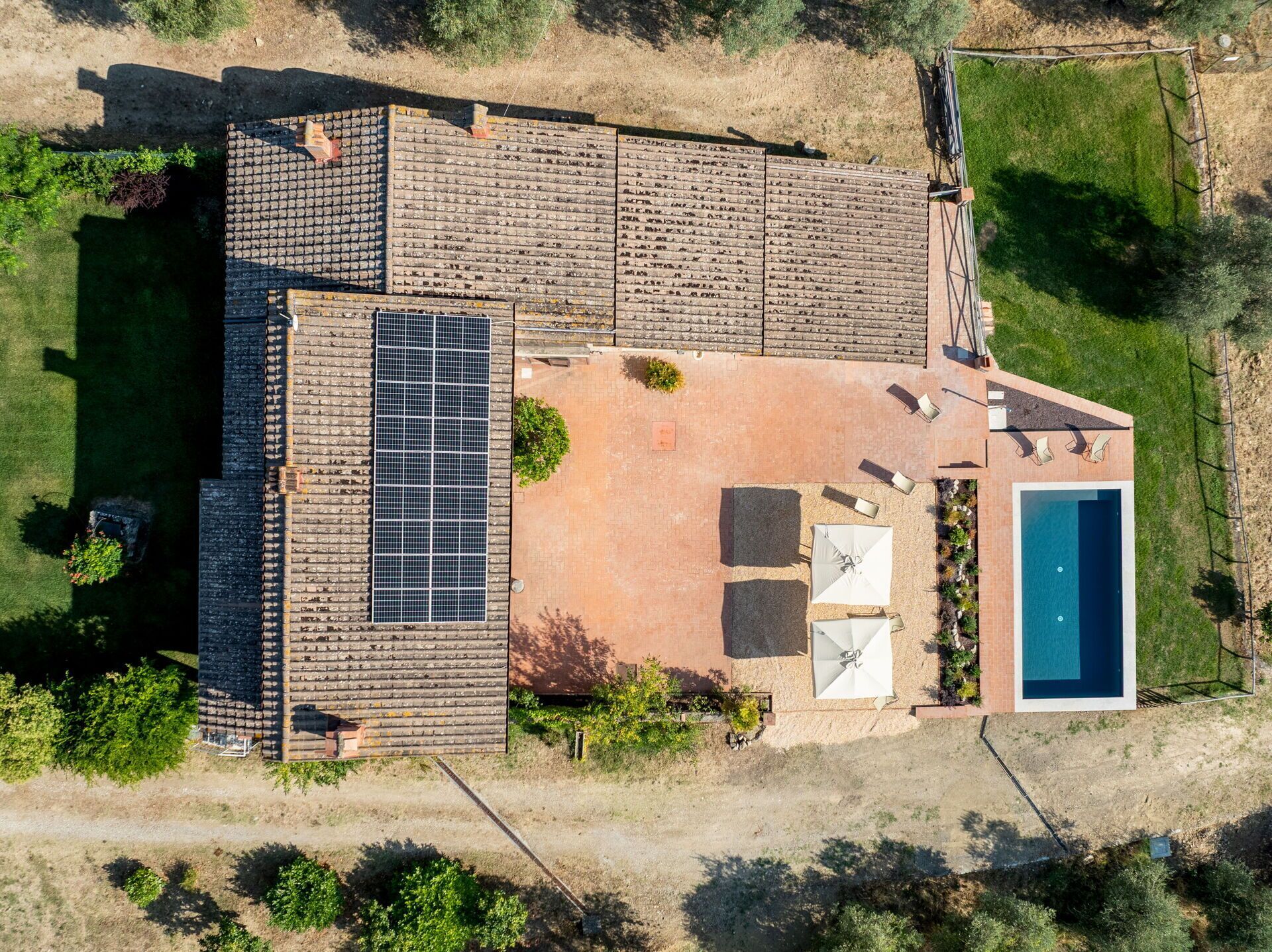 Une maison moderne dotée d’une piscine, d’un patio avec mobilier d’extérieur et d’une installation de panneaux solaires.