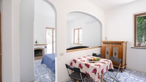 Un coin repas avec une table dressée pour deux personnes, un buffet en bois et un sol à motifs bleus.