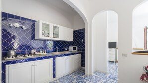 Une cuisine avec des carreaux bleus et blancs, des armoires blanches et un four à micro-ondes.