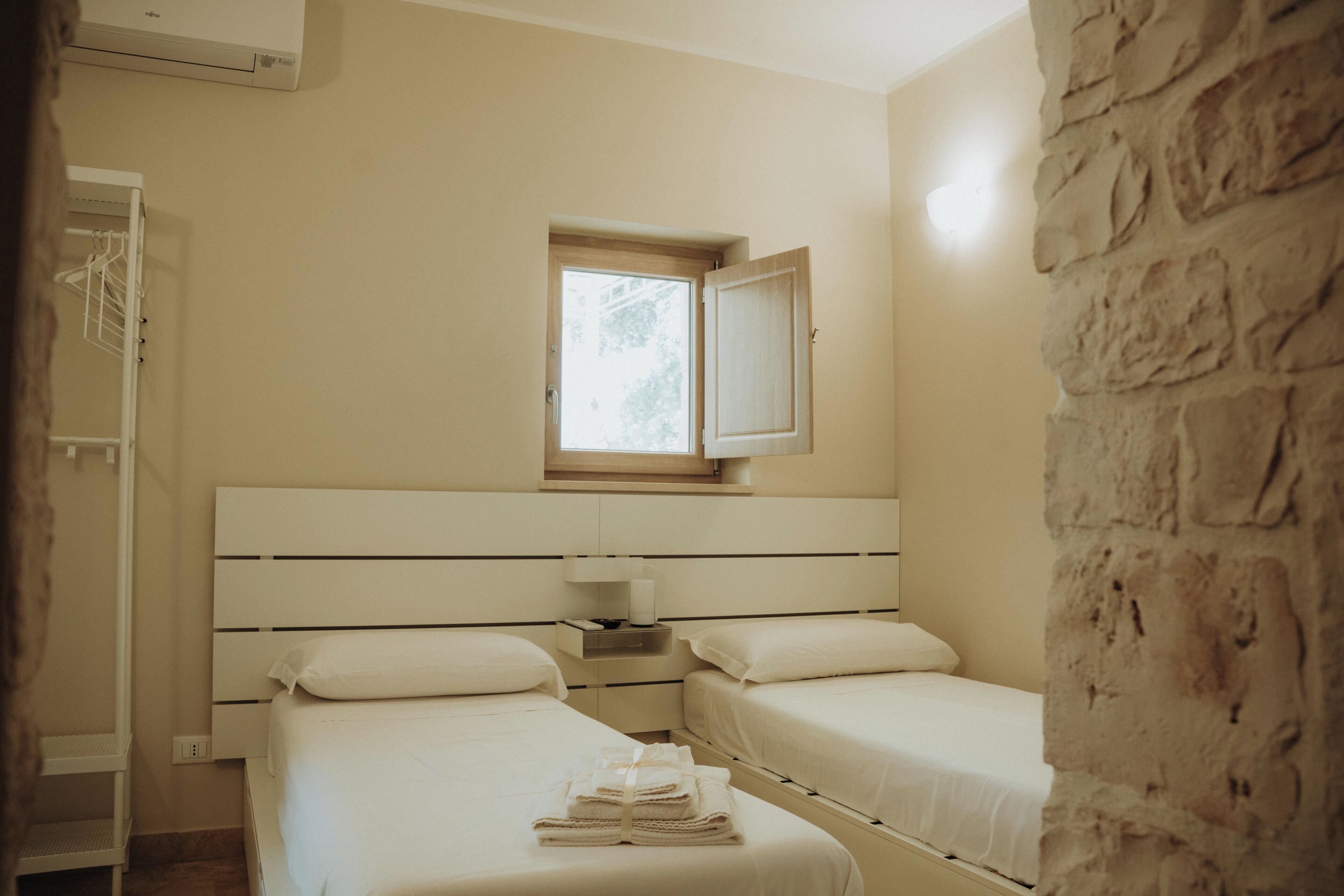 Une chambre avec deux lits, une fenêtre et un mur en pierre.