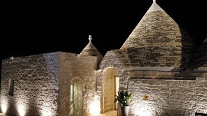 A stone building with a large arched doorway and a potted plant in front. - Quattroperle Trulli - Relax - Puglia Private Pool (Puglia)