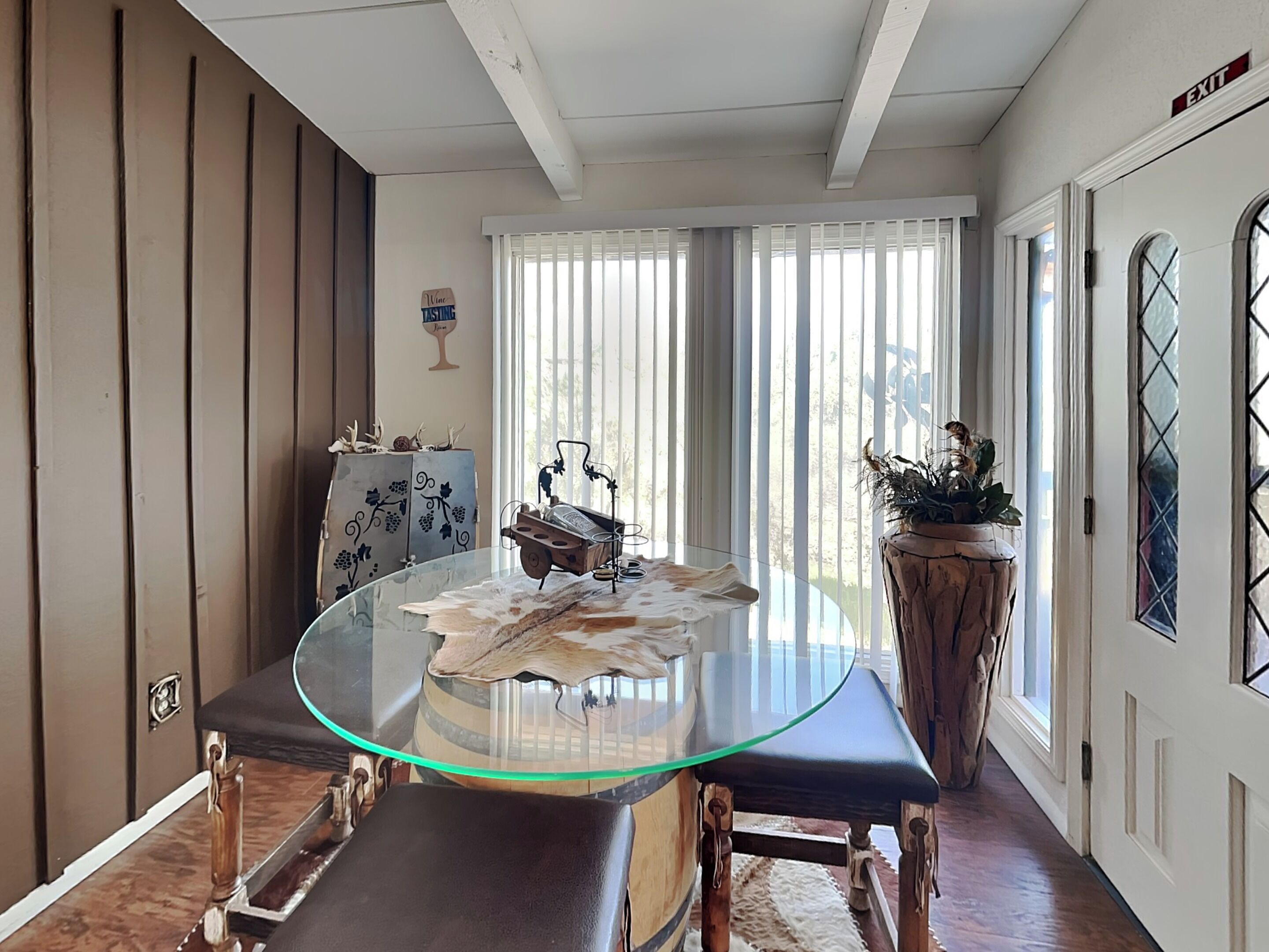 Un coin repas avec une table en verre, des bancs en bois et une plante en pot.