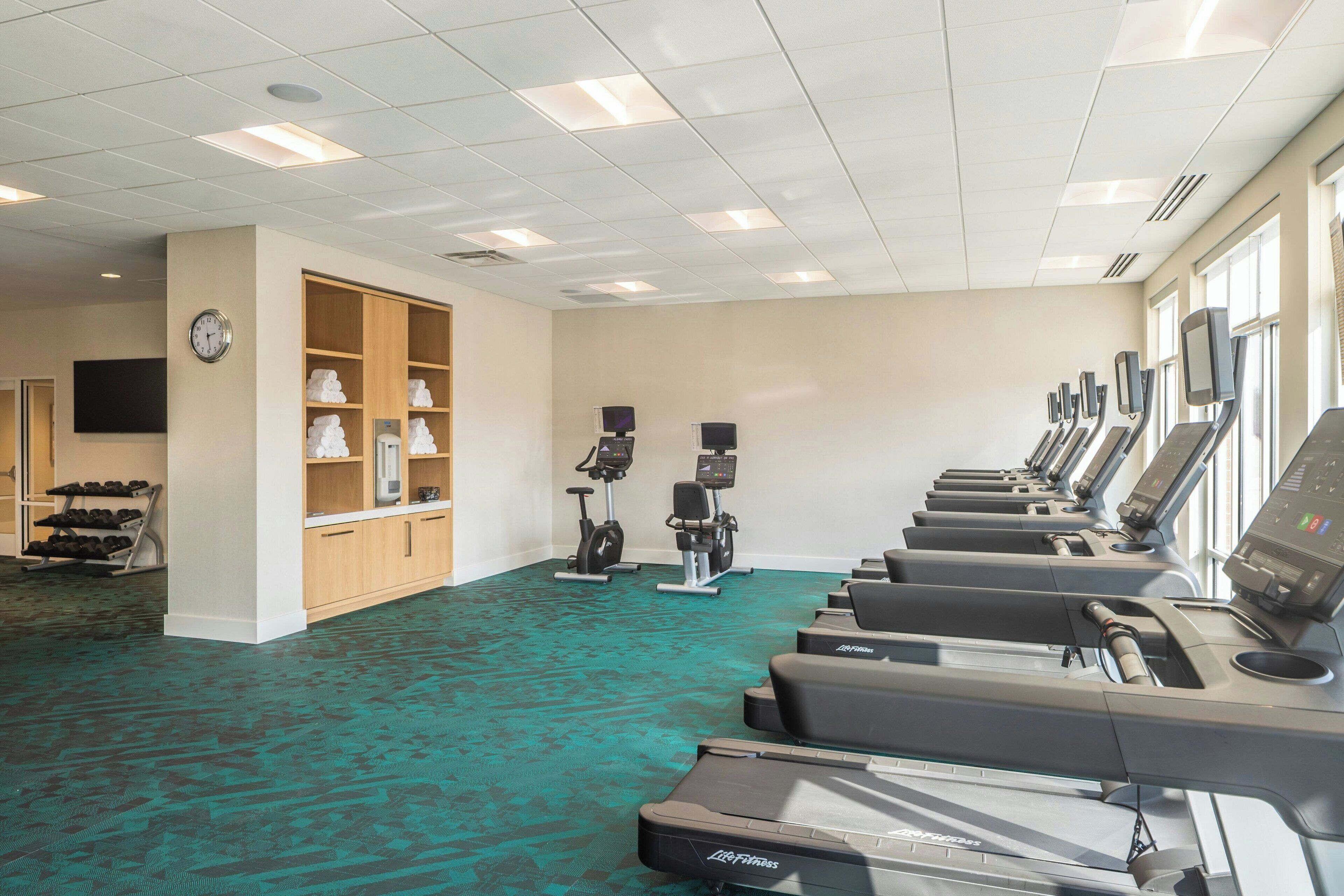 A gym with treadmills, stationary bikes, and a shoe rack.