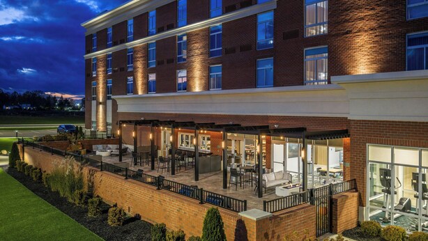 A multi-story hotel with a covered outdoor patio area, brick exterior, and large windows. - Springhill Suites BY Marriott Canfield (Canfield)