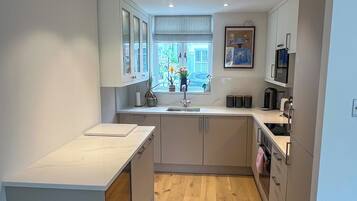 A modern kitchen with a central island, wooden flooring, and recessed lighting.