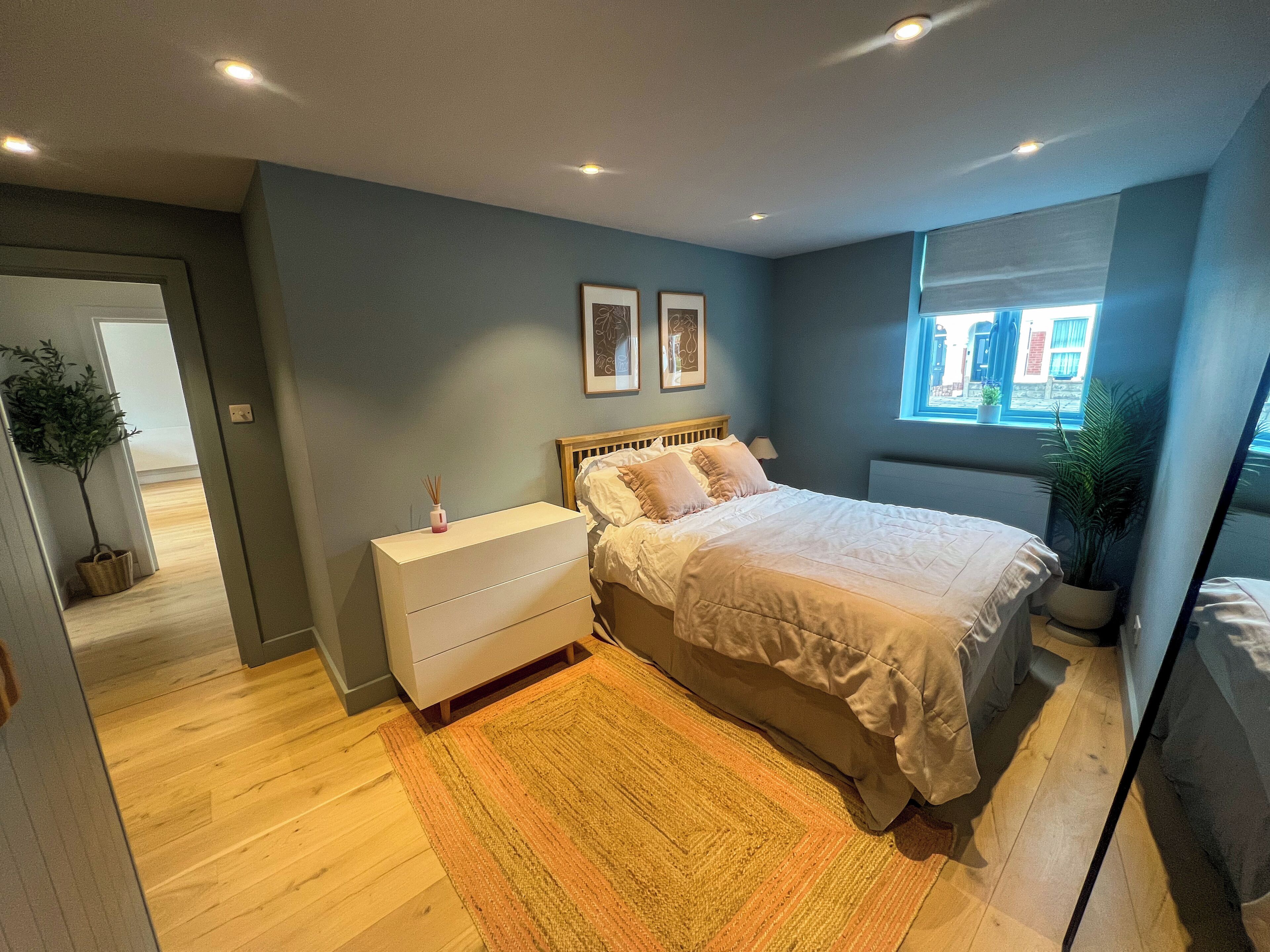 Une chambre à coucher avec un lit, une table de chevet et une fenêtre.