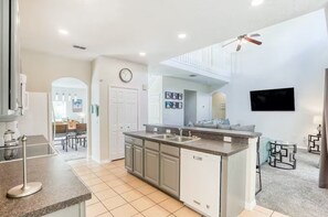 Enjoy cooking in this well-equipped kitchen with a central island, sink, and dishwasher, adjacent to a dining area with a table and chairs.