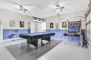 Enjoy a game of pool or shoot hoops in this recreational room featuring a pool table and basketball hoop.
