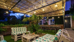 Eine Terrasse im Freien mit Holzmöbeln, einem überdachten Bereich und Lichterketten.