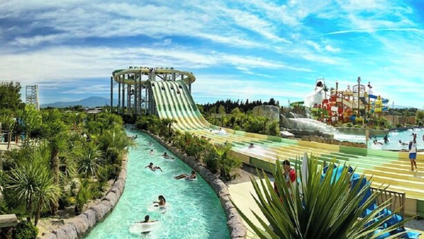 Ein Wasserpark mit einer großen Wasserrutsche, Schwimmbereichen und einem Pool.