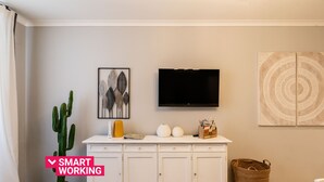A modern living room with a white cabinet, a flat-screen TV, a cactus, and decorative items. - Appartamento Adara by Wonderful Italy (Bari)