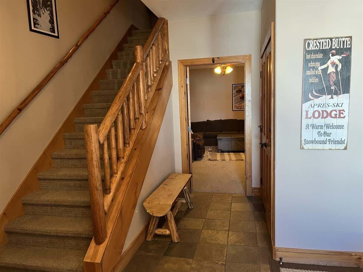 Un escalier en bois avec un banc, un panneau indicateur et une vue sur une pièce avec une cheminée.