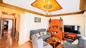 Una sala de estar con un juego de sofá, una mesa de centro, un televisor y un aparador de madera con puertas de cristal.