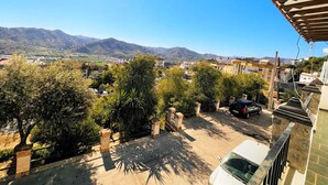 Un barrio residencial con vistas a montañas distantes, un camino pavimentado y un coche estacionado.