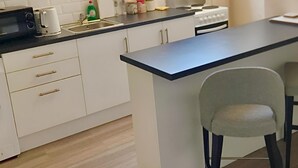 Una cocina moderna con armarios blancos, encimera negra, microondas, cafetera y estufa.