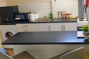 Compact kitchen with central island, microwave, coffee maker, sink, and stove with four burners.