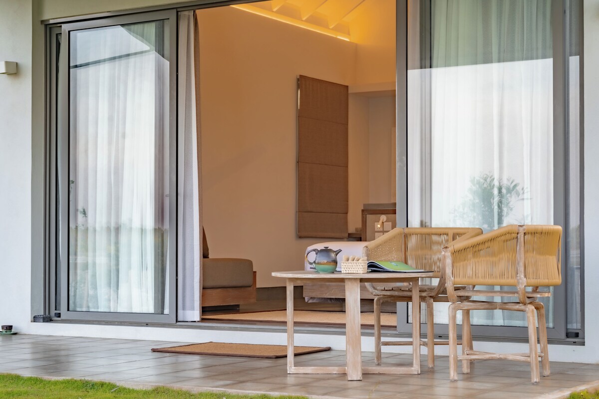 A modern interior with a sliding glass door leading to a balcony, a wooden table with chairs, and a sofa.