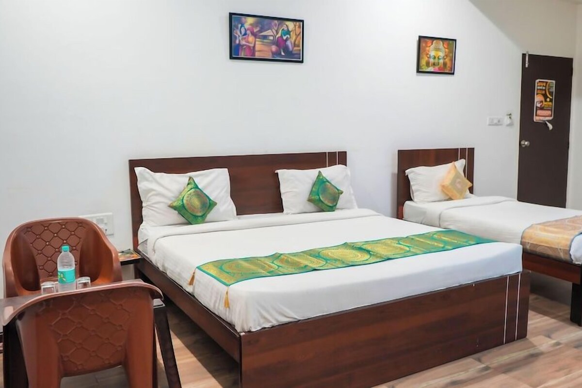 A hotel room with two single beds, a wooden headboard, a small table with a chair, and a door with a poster.