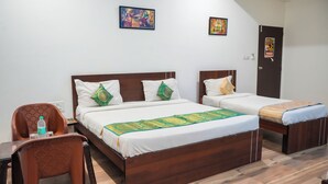A hotel room with two single beds, a wooden headboard, and a small table with a chair. - Hotel Dream villa udaipur  (Udaipur)