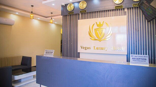A reception desk at the Vegas Luxury Hotel with clocks displaying time from Nairobi, Beijing, and New York.
