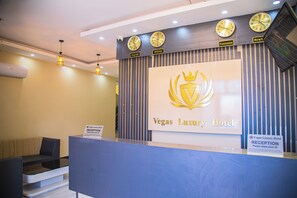 A reception desk at the Vegas Luxury Hotel with clocks displaying time from Nairobi, Beijing, and New York.